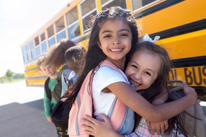 dziewczynki przytulające się przed autobusem